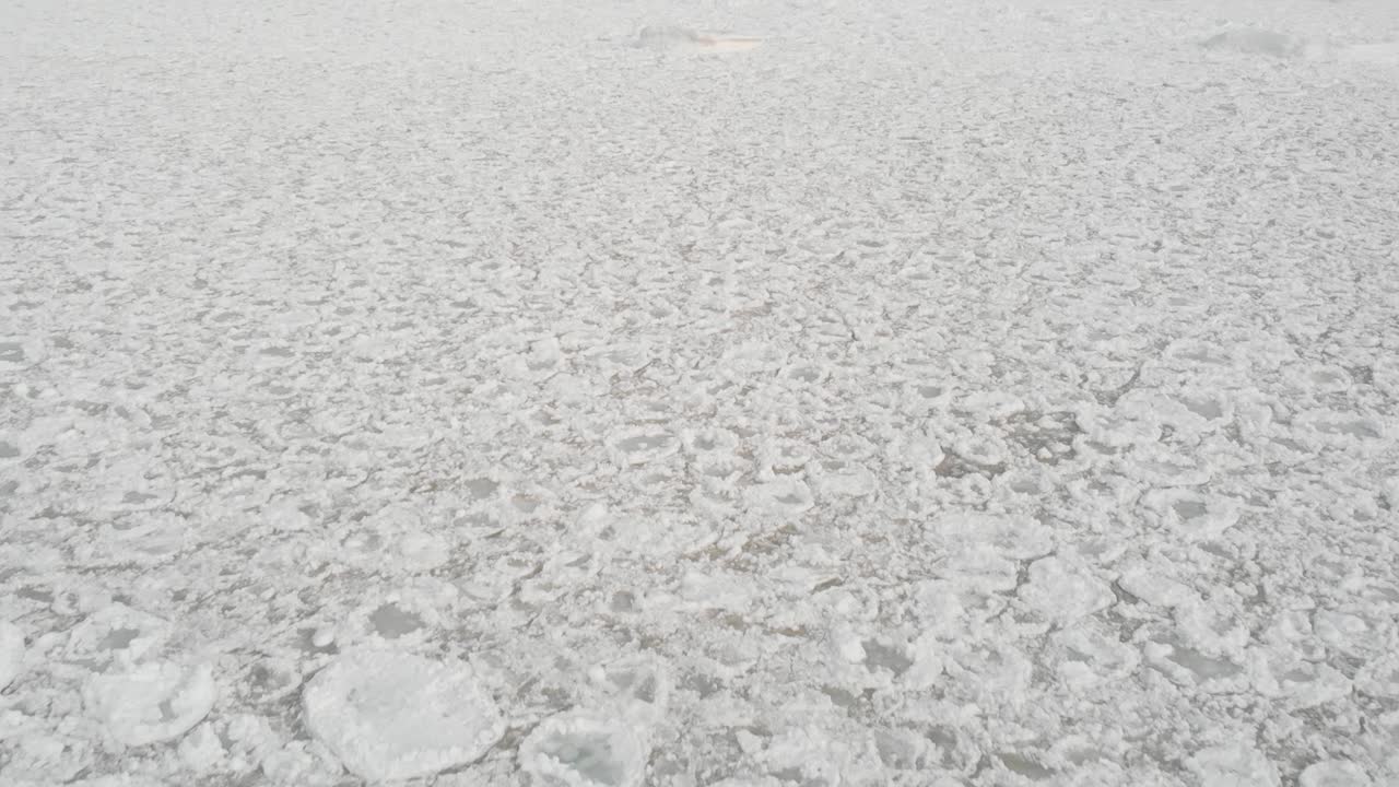 해변을 따라 얼어붙은 얼음 조각과 함께 호수 위를 비행하는 드론 영상