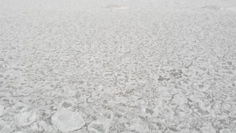 Drone-Footage-Flying-over-Lake-with-Frozen-Pieces-of-Ice-Along-Beach