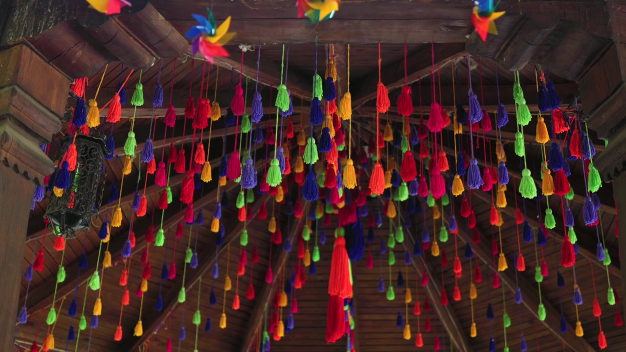Numerose nappe e girandole colorate appese e che ondeggiano dolcemente da un soffitto di legno.
