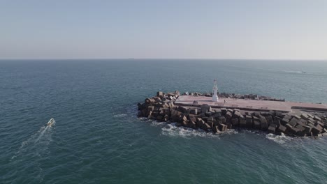 Toma-Aérea-En-órbita-Del-Rompeolas-Y-Un-Barco-Navegando