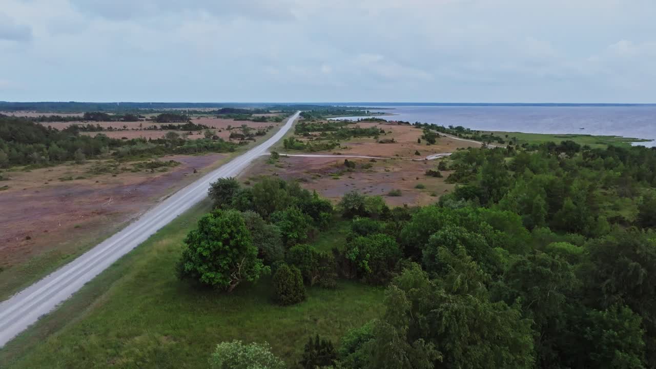 Flying over nature on the coastline besides a gravel road