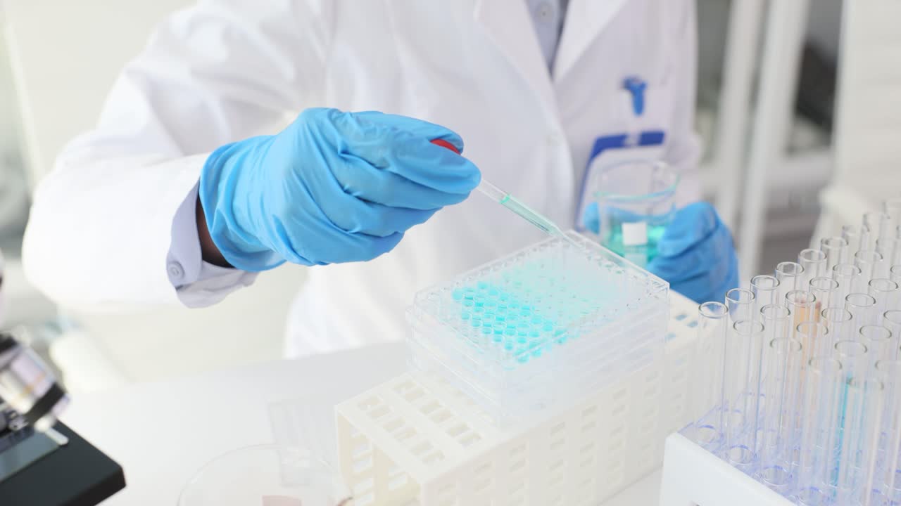 Scientist conducting an experiment with a pipette and multi-well plate in a laboratory