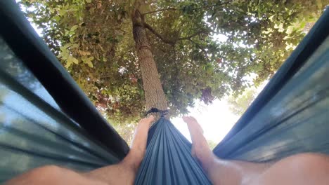 Happy-youngster-enjoying-the-day-and-swinging-left-and-right-in-the-hammock