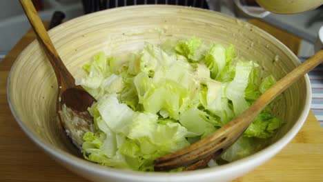 adding special sauce into caesar salad inside deep bowl