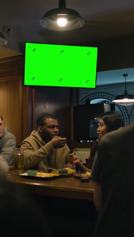 Vertical-shot-of-African-American-fan-celebrating-with-friends-when-football-team-scores-goal-and-wins-the-tournament.-Group-of-multicultural-friends-watch-live-soccer-match-sitting-in-sports-bar-or-pub.