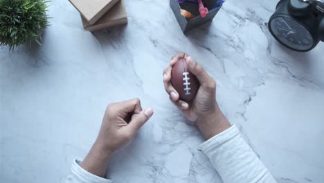 hands holding a football on a marble desk