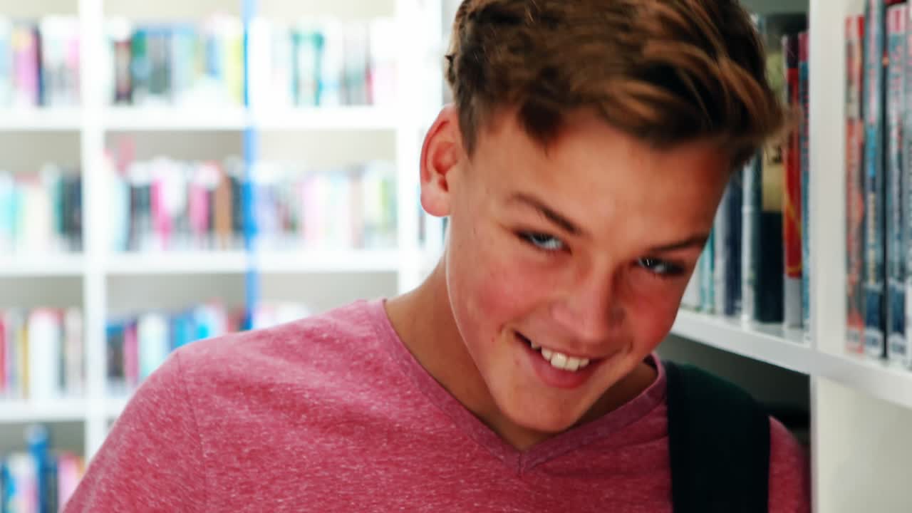 도서관 에 서 있는 미소 짓는 학교 소년