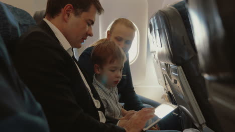 familia de tres en el avión con teléfono inteligente y tableta pc