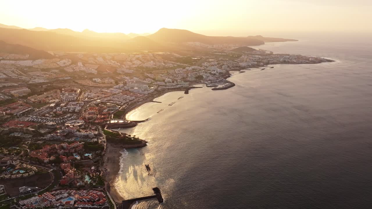 Sunlight spreads over Tenerife coastline, bathing Fanabe Beach in golden glow