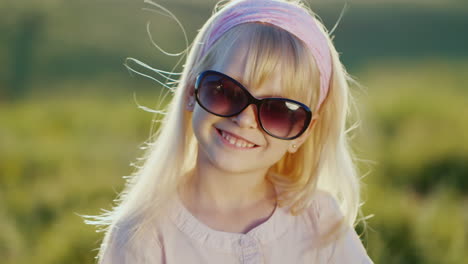 chica rubia divertida con gafas de sol mira a la cámara sonriendo