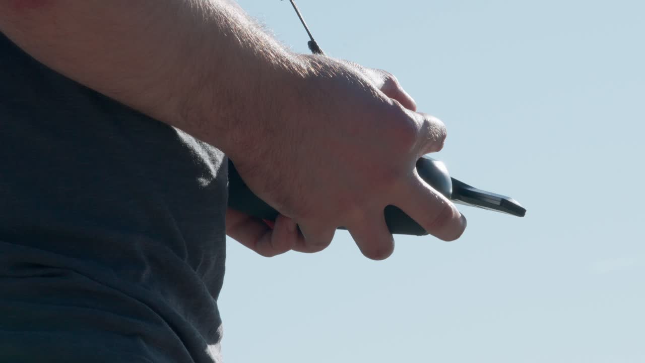 Bir dronu uçurmak için radyo vericisi tutan ve kontrol çubuklarını hareket ettiren pilot ellerinin yakın görünümü.