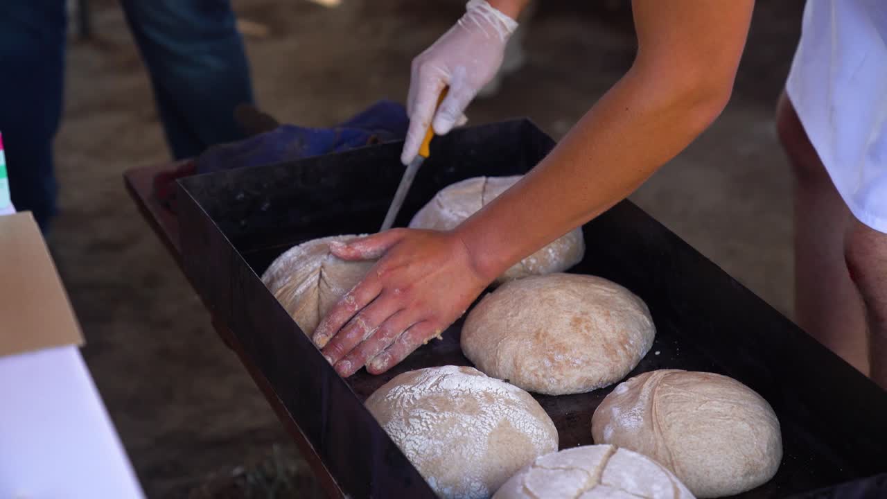 Hands cutting dough in preparation for baking artisan bread