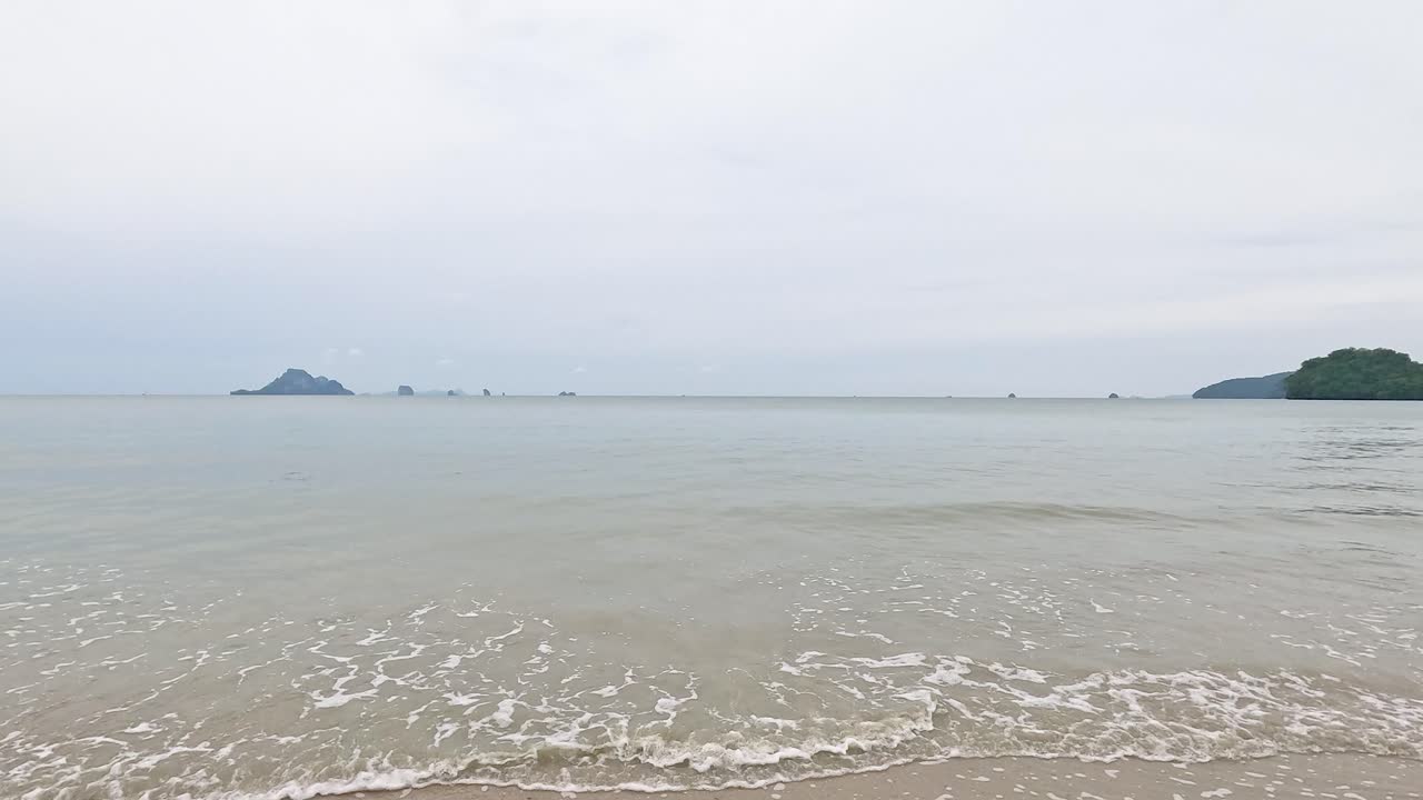 부드러운 물결은 흐린 하늘 아래, 조용하고 진정시키는 분위기를 만들어, 크라비의 노파라트 타라 해변의 해변을 고 있습니다.