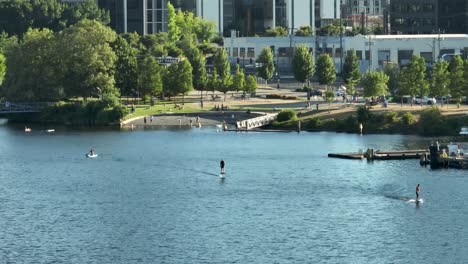 people riding electric surfboards with south lake union's tech headquarters looming in the backdrop