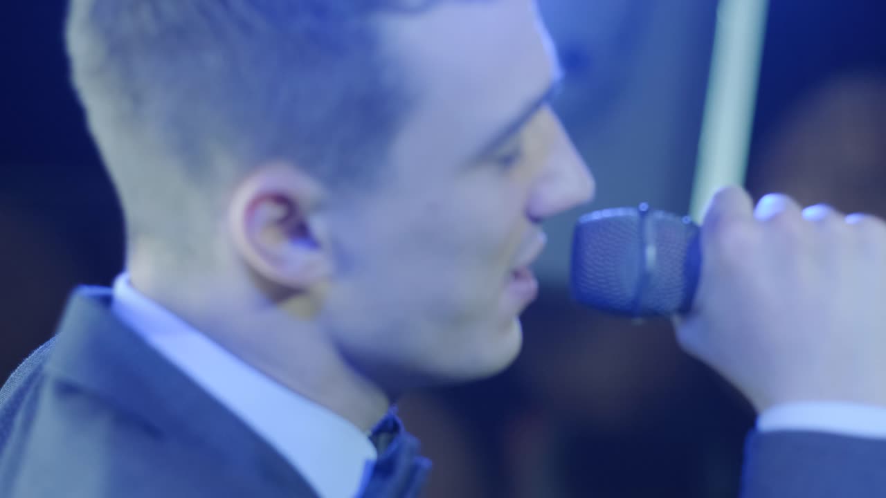 hombre cantando una canción en el micrófono durante la actuación en el escenario en un concierto de rock. cerca de hombre cantante de estrella de rock en el concierto de música en un fondo de luz colorido