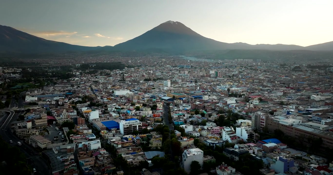 Laaja dronenäkymä Arequipan kaupunkimaisemasta, valkoisesta kaupungista, Misti-tulivuoren piirtyessä siluetiksi auringonnousussa, Peru. Eteenpäin suuntautuva ilmakuva.