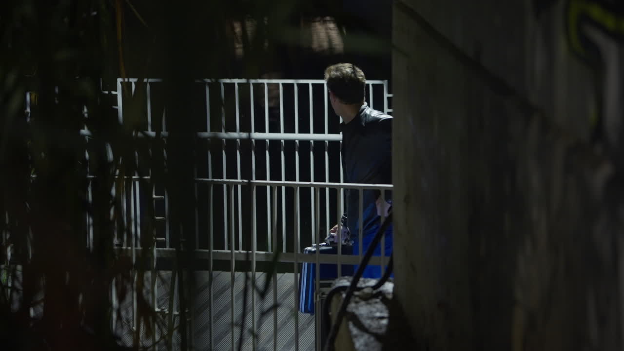 Suspicious exchange of envelope and briefcase under a bridge in a park at night. Dirty shady business transaction and meeting by spy agent insider. Selling secrets or information for bribe money fraud