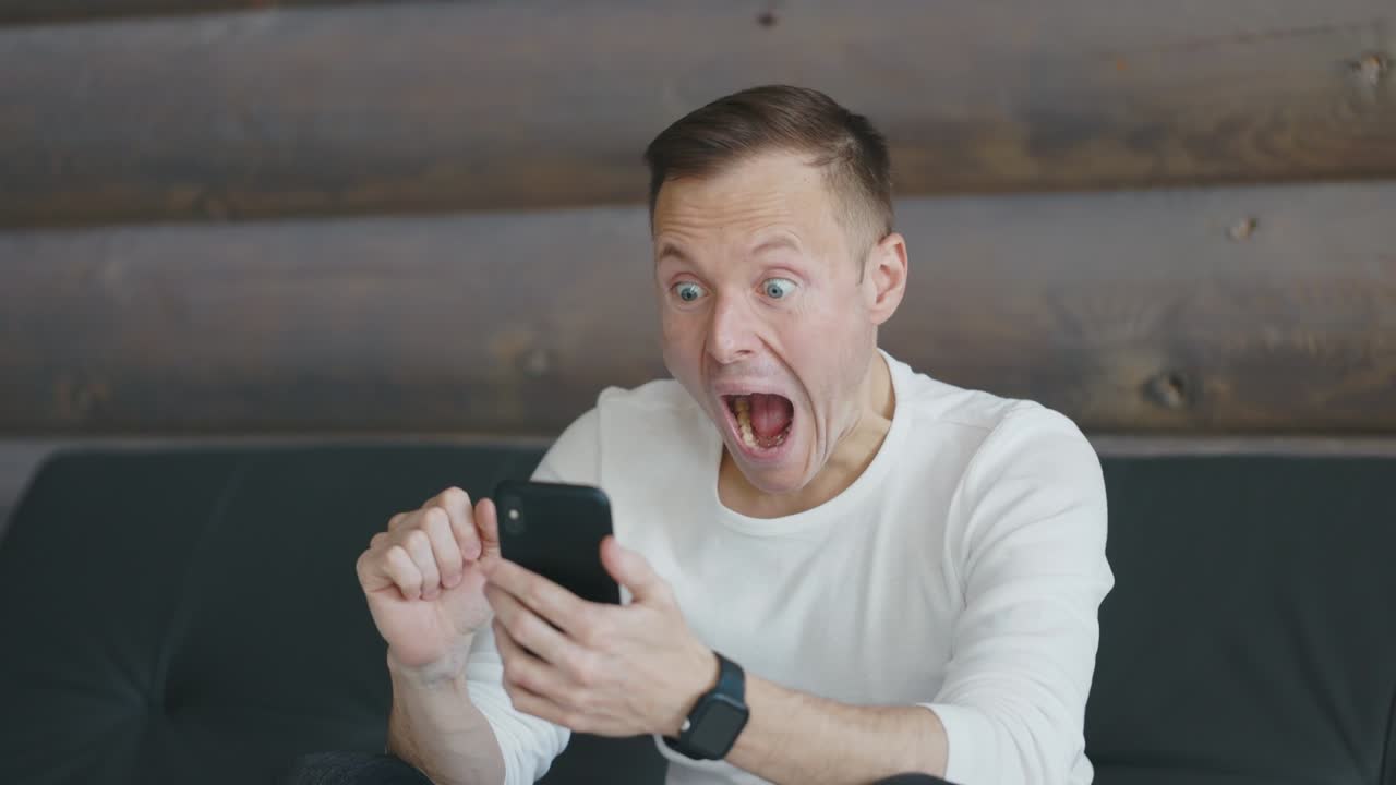 emocionado y agradablemente sorprendido el hombre se regocija en el mensaje en su teléfono inteligente