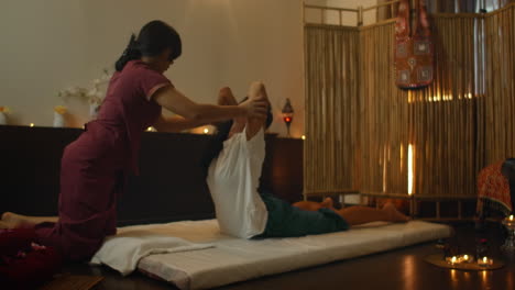 alternative chinese medicine an asian woman performs therapeutic massage on the back and legs of a caucasian woman lying on a couch. aromatherapy and manual therapy by chinese masters.