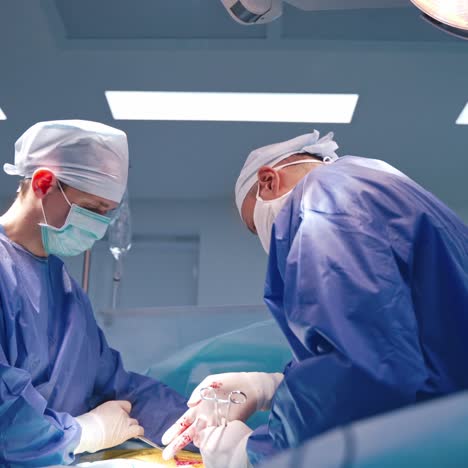 side view of surgeons at working process. male doctors in blue medical uniform performing an operation in the modern operating room.