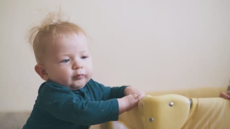 baby in green clothes plays with elder sister at playpen