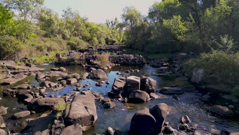 Drone-flys-low-over-rocky-boulder-strewn-river-in-Sierra-de-Andujar-nature-reserve-Spain