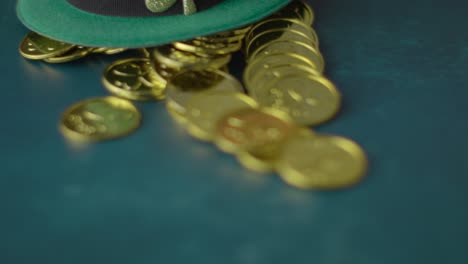foto de estudio de sombrero de copa de duende verde y montones de monedas de oro para celebrar el día 10 de san patricio