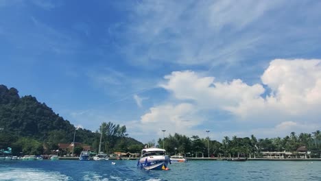 fast boat pulls away from the from the shore revealing a beautiful island