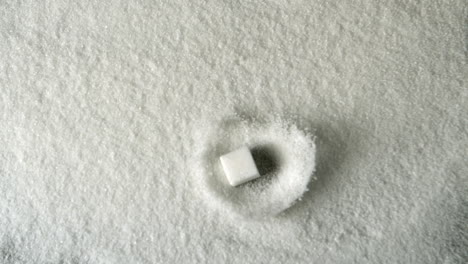 cubo de azúcar cayendo en una pila de azúcar