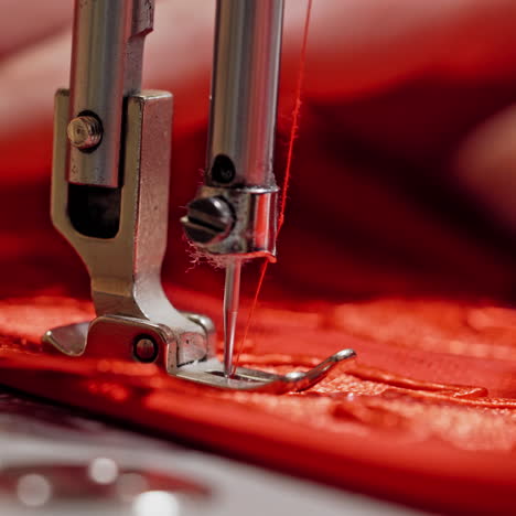 process of sewing machine working with red fabric. woman's hands at work on metal sewing machine with bright red material. close-up