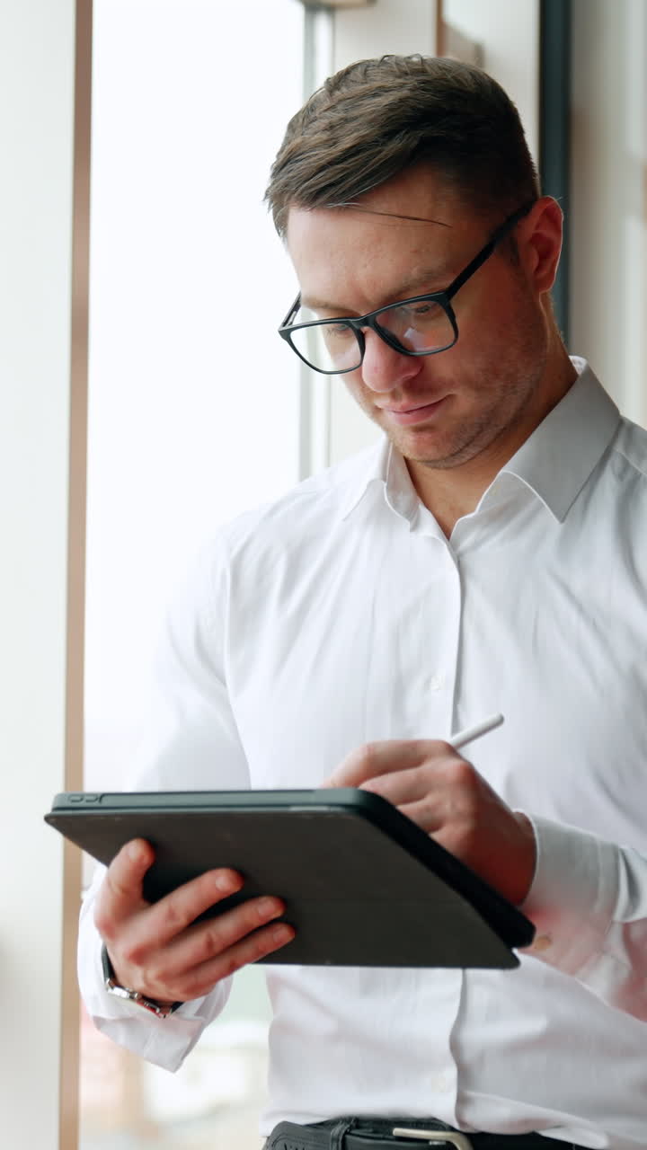 Pensive Caucasian businessman holding an I-pad and stylus pencil
