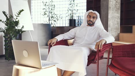 handsome man with traditional clothes working in an office of dubai