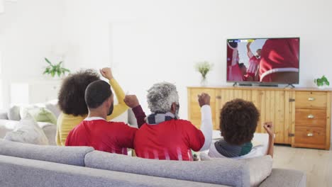 African-american-family-watching-tv-with-diverse-male-soccer-players-playing-match-on-screen