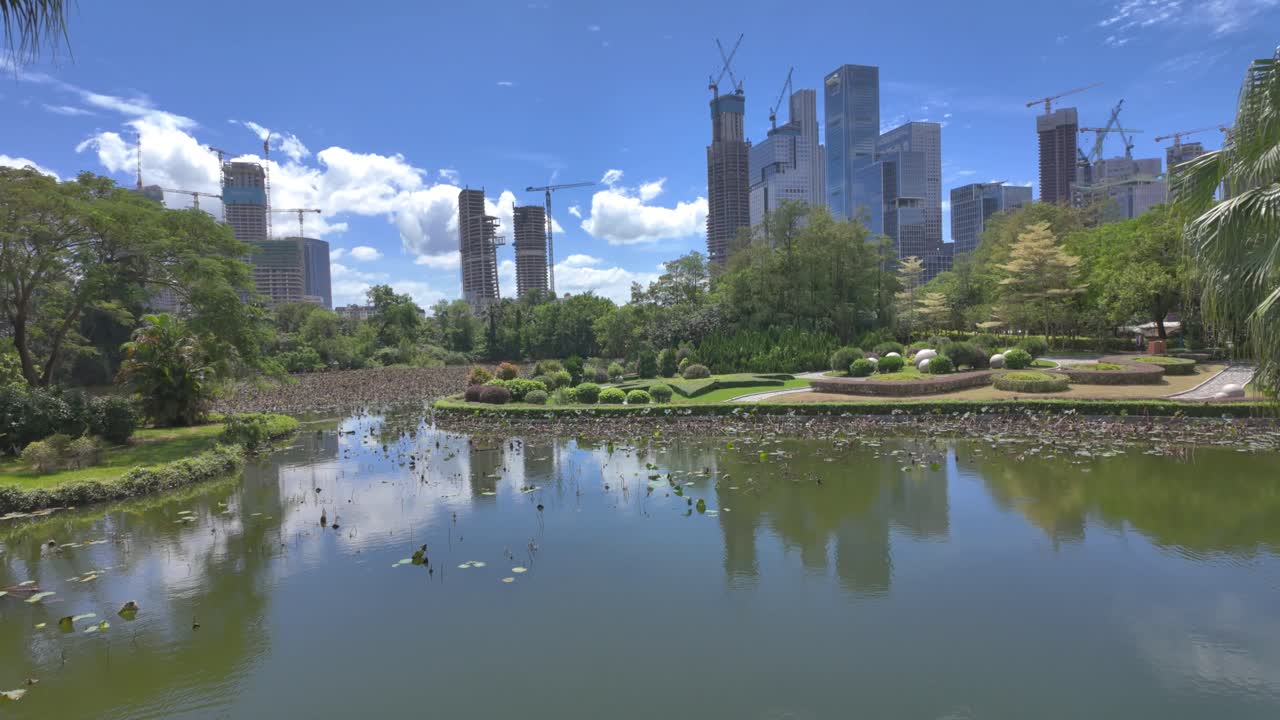 Vídeo em 4K de um lago artificial em um parque temático chinês com arranha-céus modernos em construção no plano de fundo