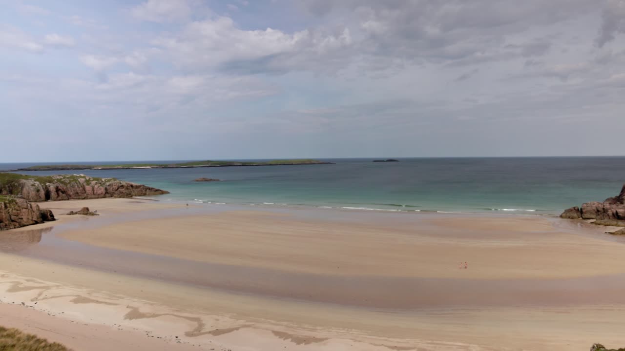 Tourists walking on the beautiful Ceannabeinne Beach with turquoise water
