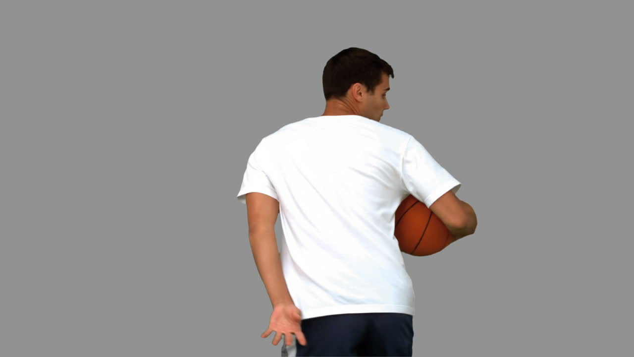 hombre driblando con una pelota de baloncesto en la pantalla gris