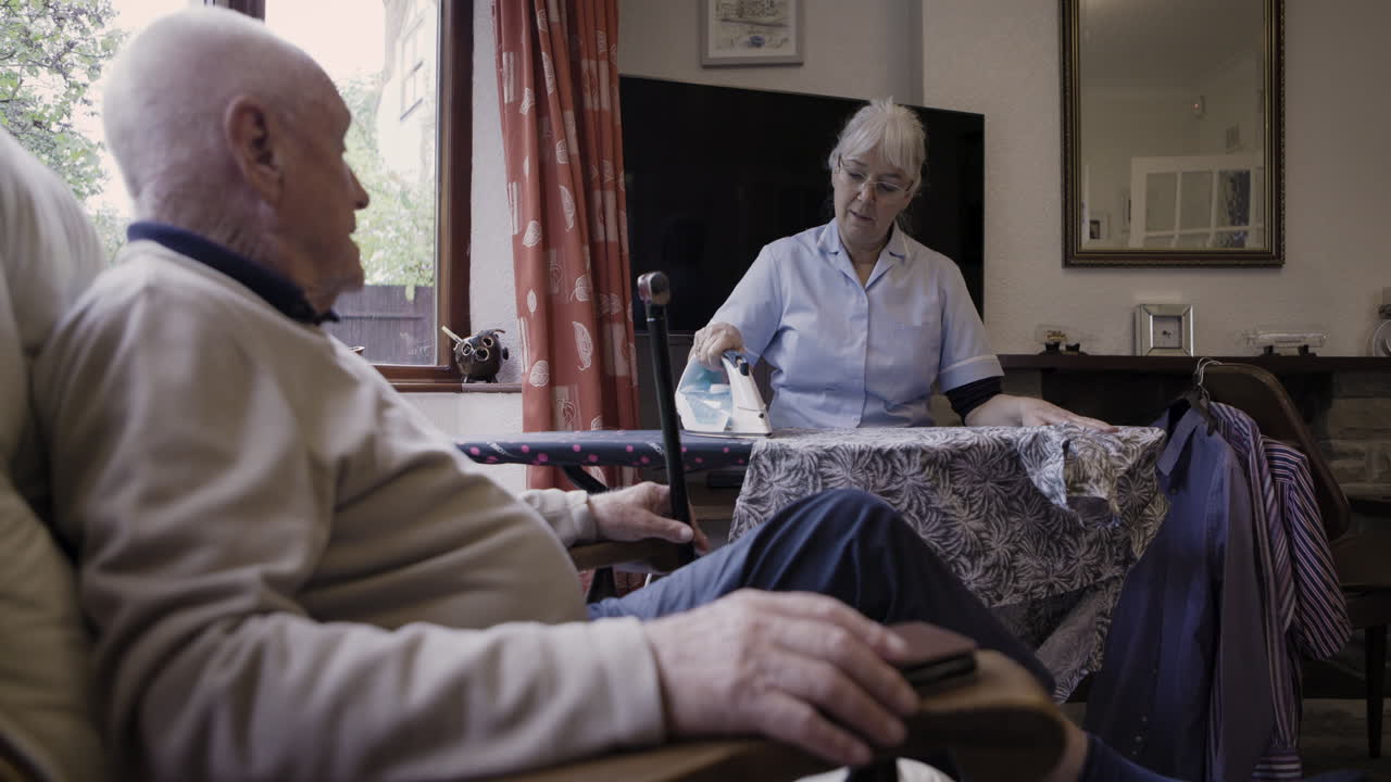 Elderly man receiving assistance from a caregiver at home