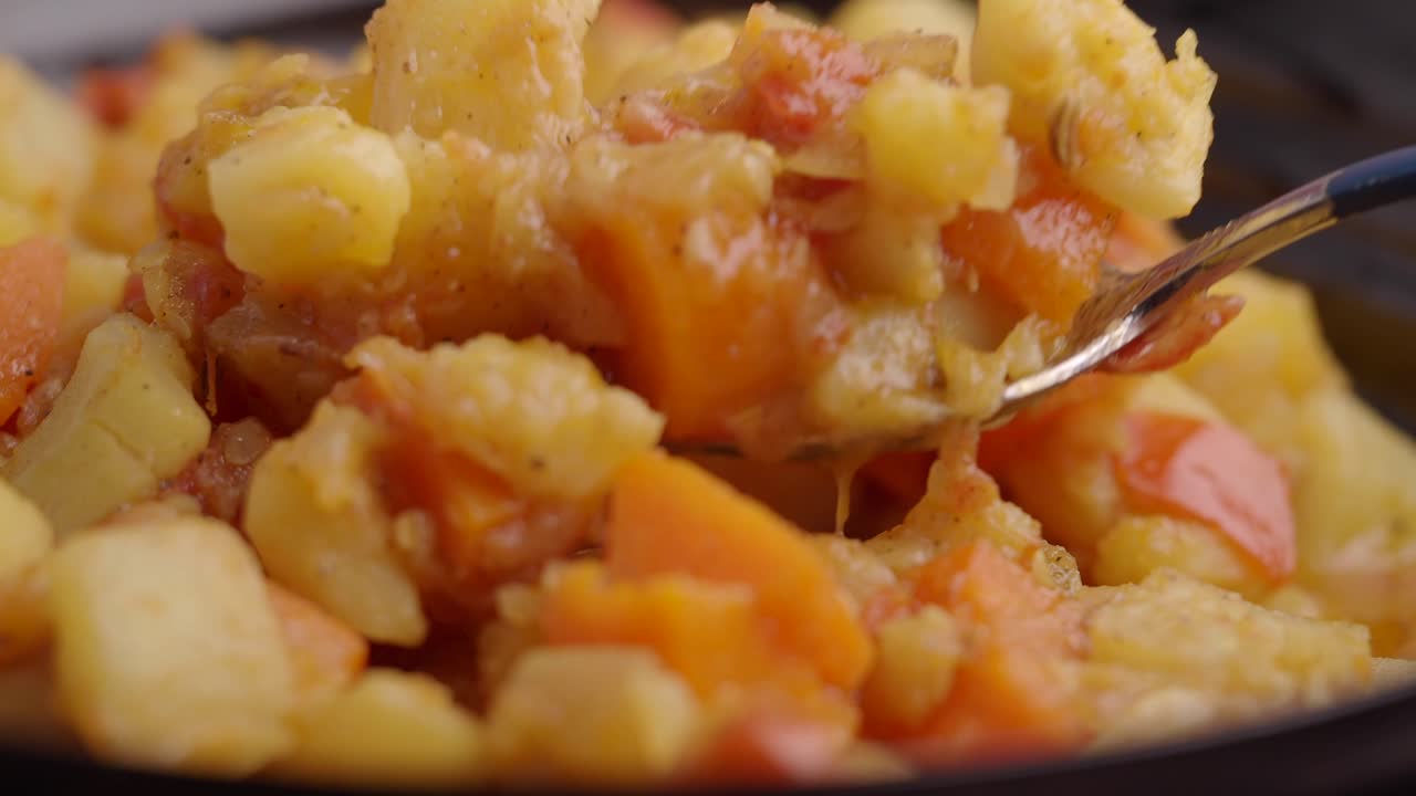 Primo piano di patate e carote cotte a dadini raccolte con una forchetta