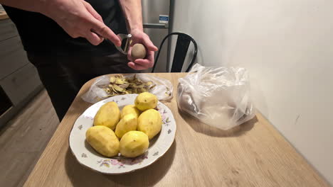 Peeling-potatoes-skin-using-potato-peeler-by-hand-in-the-kitchen-by-chef