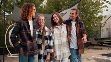 Two-boys-and-two-girls-in-checkered-shirts-are-walking-and-hugging.-Two-guys-high-five-each-other.-Rest-in-the-country-house