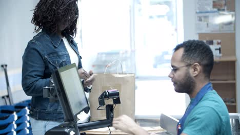 smiling woman paying with credit card and packing food