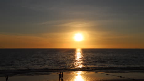 sunset at the beach with people passing