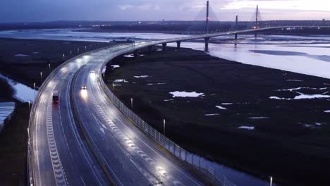 Aerial-view-Mersey-gateway-illuminated-freeway-bridge-overpass-lanes-early-morning-sunrise-left-orbiting-shot