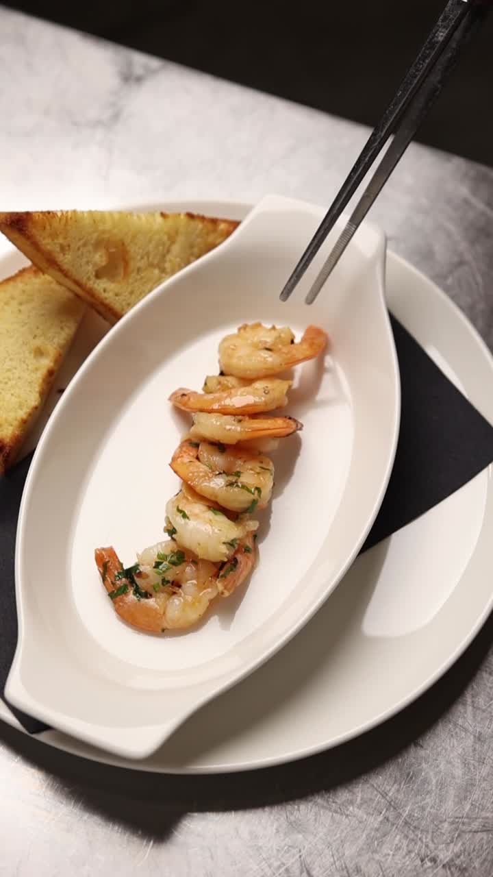 Chef Plating Cooked Shrimp with Tongs in a Restaurant Kitchen