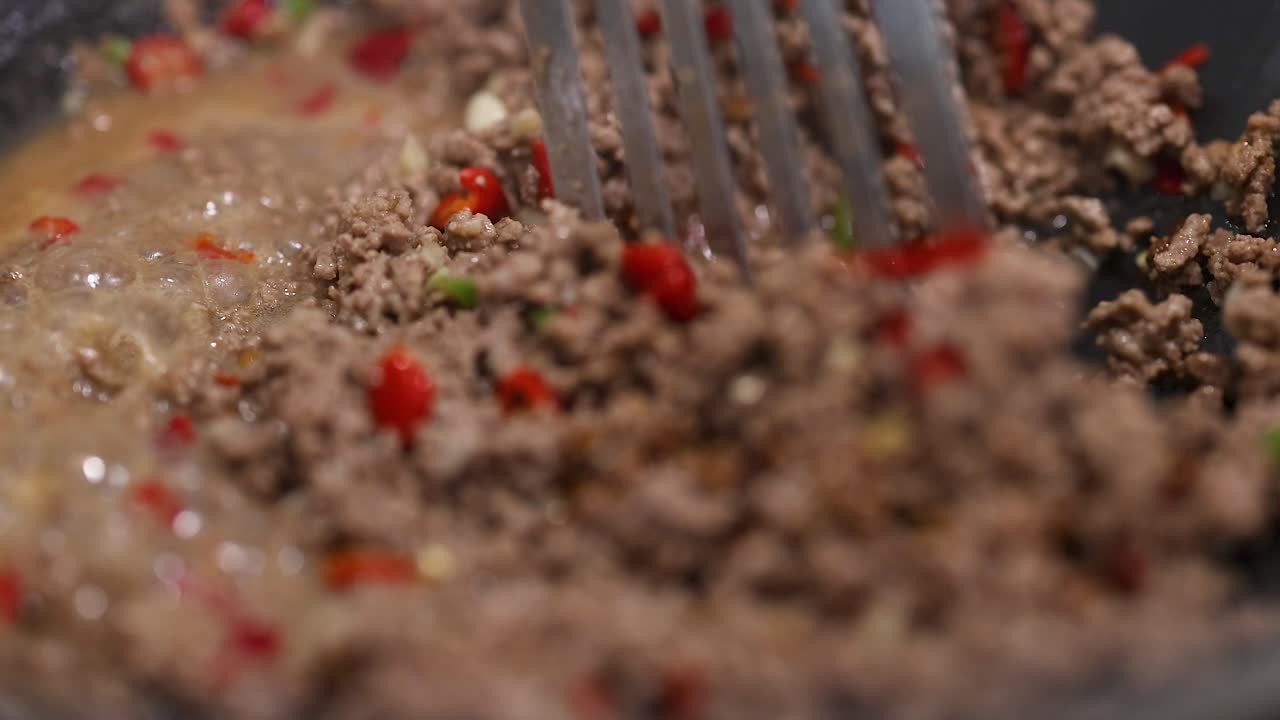 Close-up of beef stir-fry cooking with vibrant peppers. Rich textures and colors under warm lighting in a kitchen setting