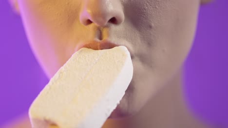cerca de la boca de la mujer comiendo helado de sabor a vainilla y lamendo los labios con la lengua, toma de estudio