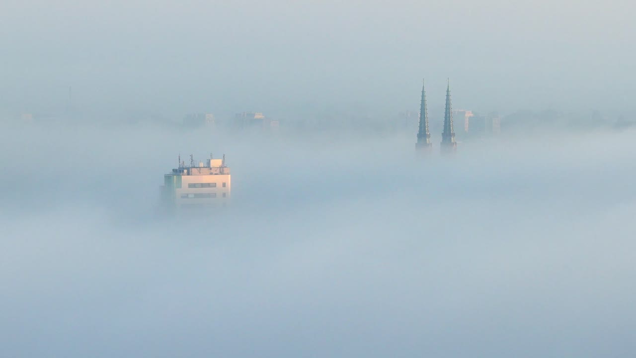 Aerial view of Warsaw's Praga in fog with cathedral towers visible