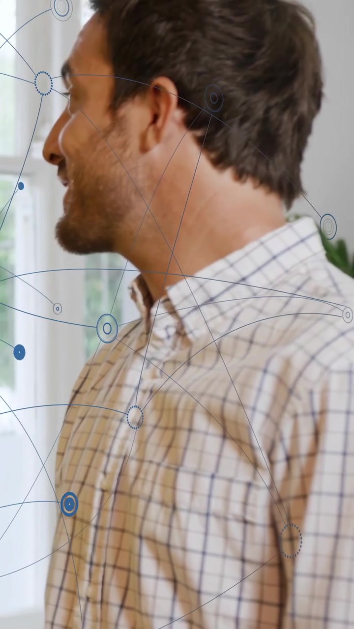 Vertical video: Man shifting and speaking at window, starting blue network overlay in tech demo