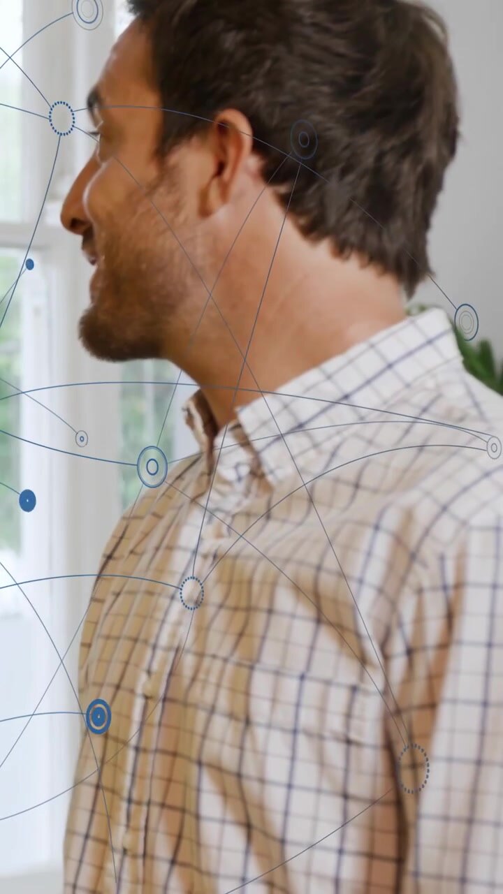 Vertical video: Man shifting and speaking at window, starting blue network overlay in tech demo