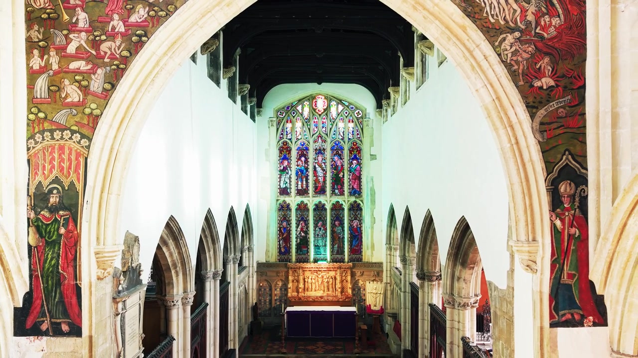 Symmetrische Innenansicht durch den mittelalterlichen Weltgerichtsbogen zum Choraltar und Buntglasfenster in der St. Thomas Kirche Salisbury.